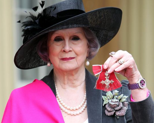 April Ashley holding her MBE  outside of Buckingham Palace